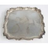 An Edwardian silver salver, of shaped square form with scrolling detail to rim, bearing armorial and