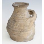 A wheel thrown earthenware vessel, of squat form with grooved body and loop handle, Medieval,