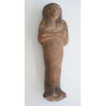 An Egyptian moulded and tooled shabti figure, in typical standing pose with arms crossed upon the