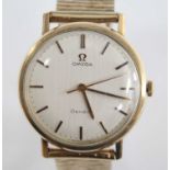 A yellow metal gent's Omega manual wind wristwatch, having a round cream baton dial and fitted to