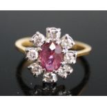 An 18ct yellow and white gold, ruby and diamond oval cluster ring, featuring a centre oval faceted