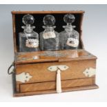 An Edwardian oak three-bottle tantalus, having silver plated mounts, hinged top opening to reveal