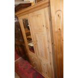 A modern pine wardrobe, having a mirrored door, panelled door, and three short drawers, w.110cm