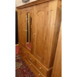 A modern pine three door wardrobe, the mirrored central door over base fitted with four short and