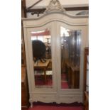 An early 20th century French painted oak double bevelled mirror door armoire, having carved floral