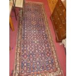 A Persian woollen blue ground hall runner, having a repeating geometric floral decorated central