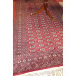 A Persian woollen red ground Bokhara rug, having trailing tramline borders, 290 x 191cm