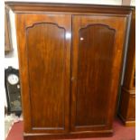 A mid-Victorian mahogany round cornered double door wardrobe, the plain arched panel doors enclosing