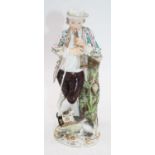 A 19th century continental porcelain figure of a male piper, in standing pose with cat at his