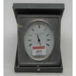 An early 20th century silver clad travel clock, the oval enamelled dial with Roman numerals and