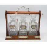 An oak cased three decanter tantalus, w.34cm, each decanter bearing a silver label, inscribed for