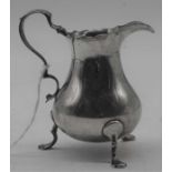 A George III silver helmet shaped cream jug, having a wavy rim, flying C-scroll handle and on cast