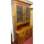 An Edwardian walnut bookcase cupboard, having coloured lead glazed upper doors, width 125cm