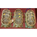 A set of three mid-20th century cast iron bulkhead ships lamps, enclosed in a wired cage, 31 x 18cm