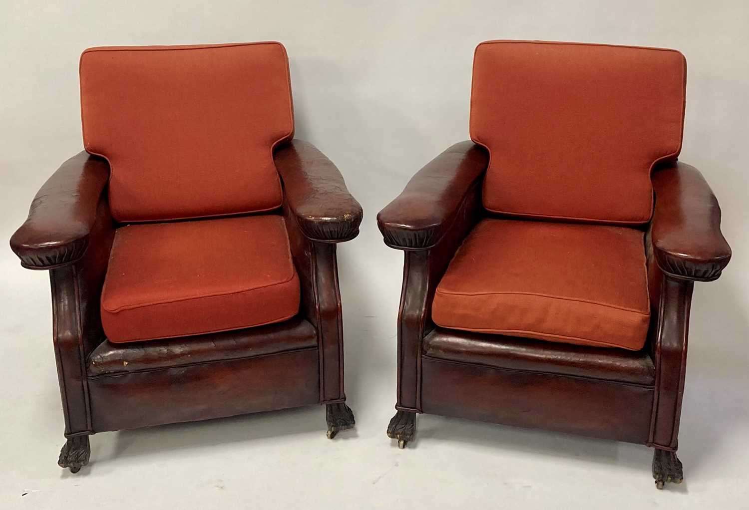 A pair of Art Deco oak framed and tan leather upholstered club armchairs, each having flattened