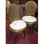 A pair of French gilt wood and cane back and seat parlour side chairs, together with a further