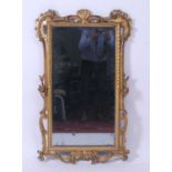 A mid-18th century carved giltwood and gesso wall mirror, the bevelled plate in a Rococo