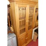 A modern pine bookcase having twin glazed upper doors, width 89cm