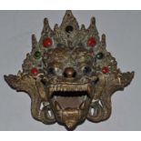 A large copper alloy tripod incense burner, cast as the head of the Mahakala with glass inset eyes