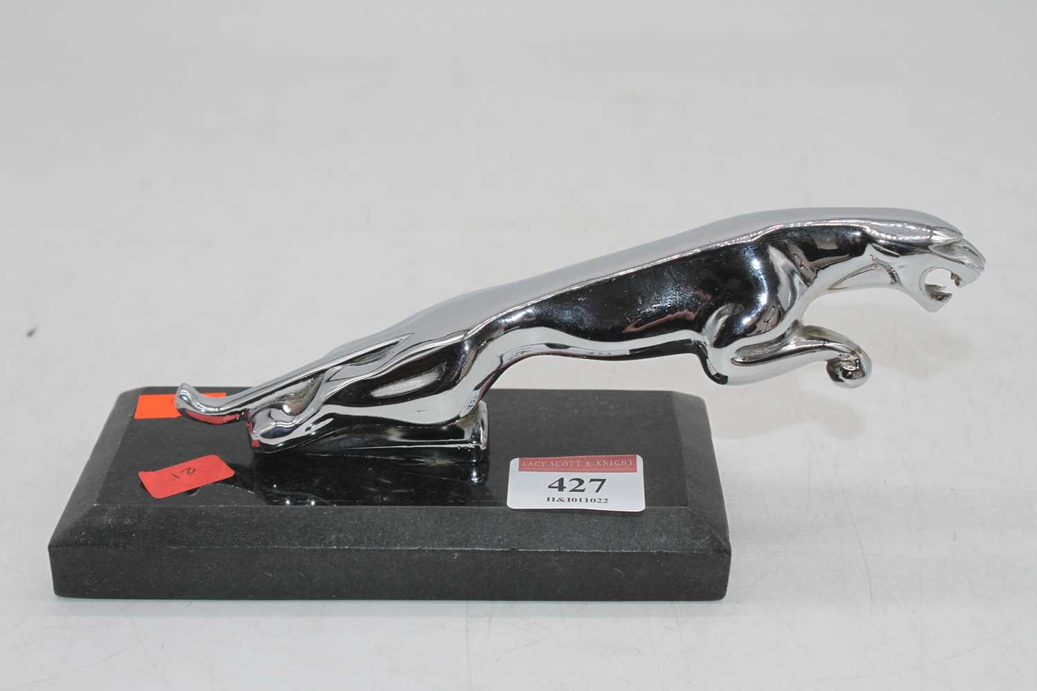 A reproduction Jaguar car mascot, mounted upon a polished black hardstone plinth, h.9cm