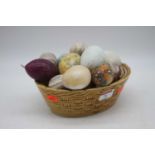 A small collection of various polished hardstone ornamental eggs in basket