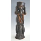 A large wooden fetish or ritual figure, carved as a male in standing pose with raised arms with