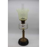 A late Victorian brass pedestal oil lamp having a vaseline tinted glass shade