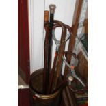 A Dutch embossed brass stick-stand; together with two shooting sticks, walking canes etc