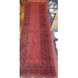 A Persian woollen red ground Bokhara hall runner, 265 x 82cm