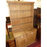 A rustic pine kitchen dresser, having three-tier open plate rack over base with two frieze drawers
