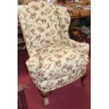 A walnut framed wing armchair in the 18th century style, the whole reupholstered in a floral