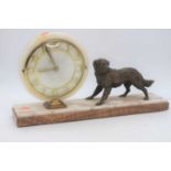An Art Deco polished hardstone mantel clock, surmounted by a spelter model of a dog, w.50cm