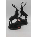 A pair of bronze stags, each shown standing upon a rock and mounted upon a black polished