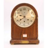 An early 20th century oak cased eight-day mantel clock, the silvered dial showing Arabic numerals,