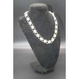 A Victorian white metal sectional necklace, having alternating engraved oval beads united by plain