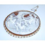 A yellow metal carved shell cameo brooch, depicting a country scene of women and children playing,