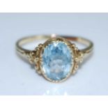 A yellow metal aquamarine dress ring, having an oval faceted aquamarine within a scrollwork