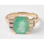 A yellow and white metal emerald dress ring, featuring a rectangular cut emerald in a four-claw