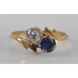 An 18ct yellow and white gold, sapphire and diamond two stone crossover ring, comprising a round