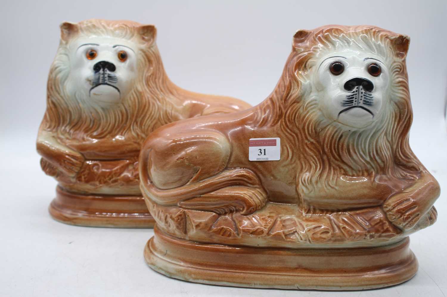 A pair of Sadler hollow moulded figures, each in the form of a recumbent lion with glass eyes having