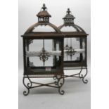 A pair of contemporary burnished metal and glazed outside lanterns, each having a domed top above