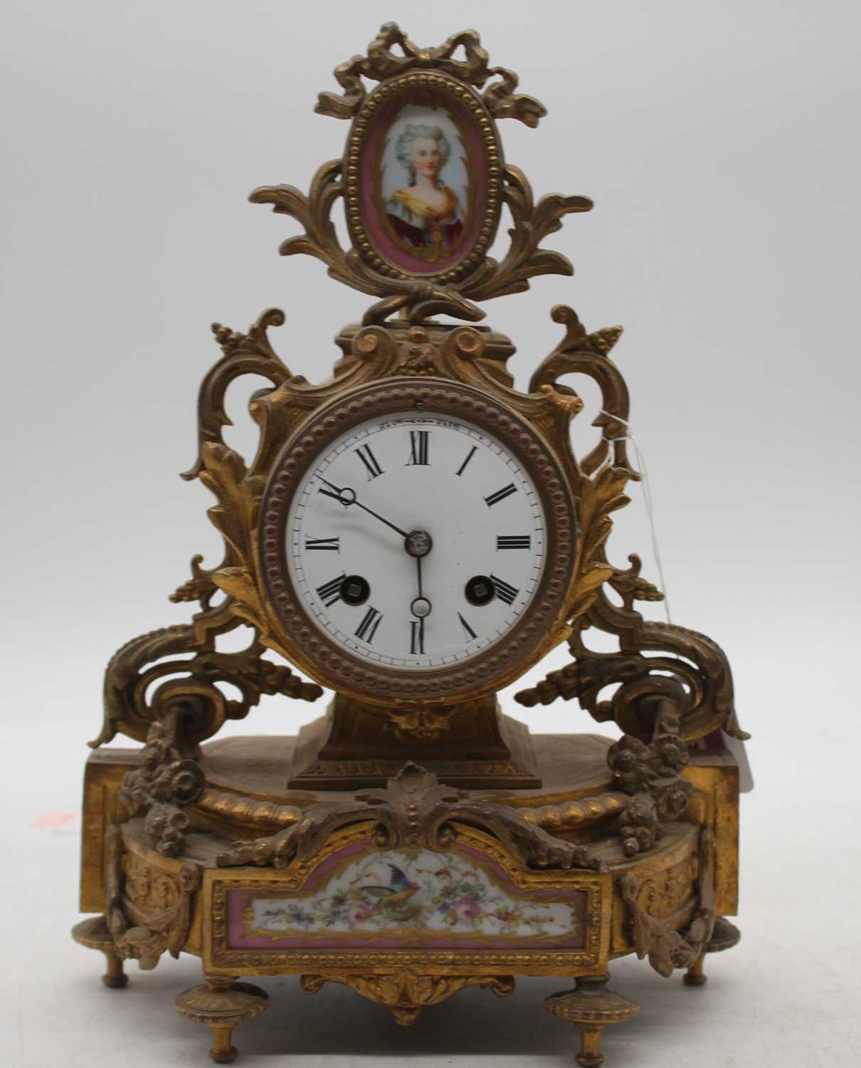 A late 19th century French gilt metal and porcelain inset mantel clock, having an enamel dial with