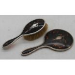 A George V silver, tortoiseshell and piquework hand mirror; together with a matching hairbrush (2)