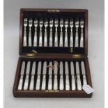 A walnut cased set of twelve silver and mother of pearl handled dessert knives and forks,