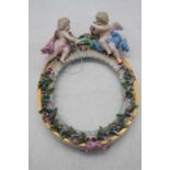 An early 20th century Meissen porcelain oval frame, surmounted by putti, h.24cm, w.17cmSeveral