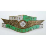 A Grey-Green Geo. Ewer & Co Ltd. brass and enamelled coach drivers cap badge, with winged wheel