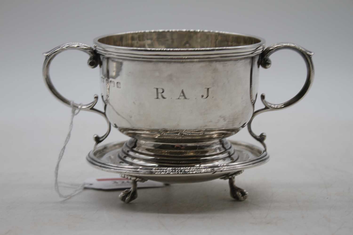 A George V silver cup having twin leaf capped scrolling handles, engraved RAJ within a raised