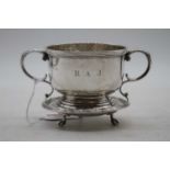 A George V silver cup having twin leaf capped scrolling handles, engraved RAJ within a raised