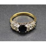 A modern 18ct gold, sapphire and diamond set dress ring, arranged as a centre four claw set oval cut