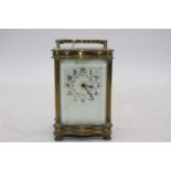 An early 20th century lacquered brass carriage clock of serpentine outline having enamelled dial